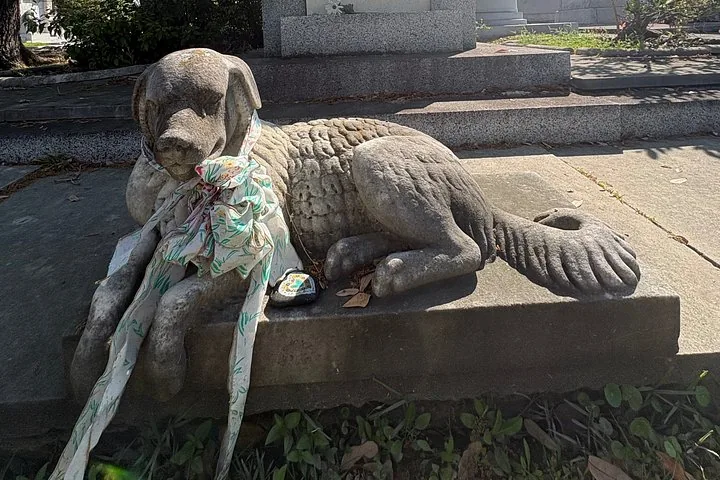A stone statue of a dog lying on a grave.