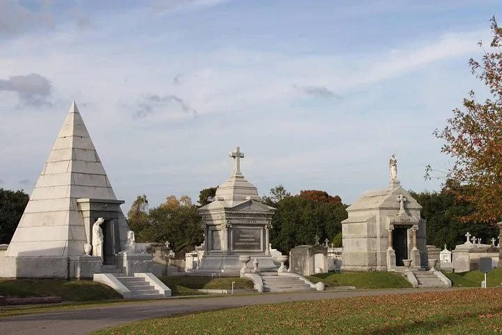 Several ornate mausoleums, including a pyramid-shaped one, in a cemetery.