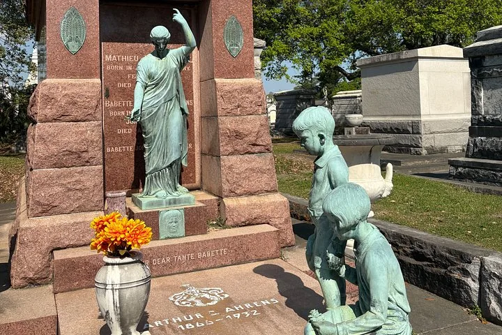 A family tomb with bronze statues of children and a woman.