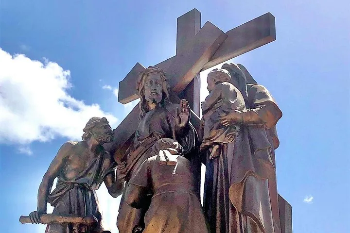 A bronze sculptural monument featuring several figures and a large cross.