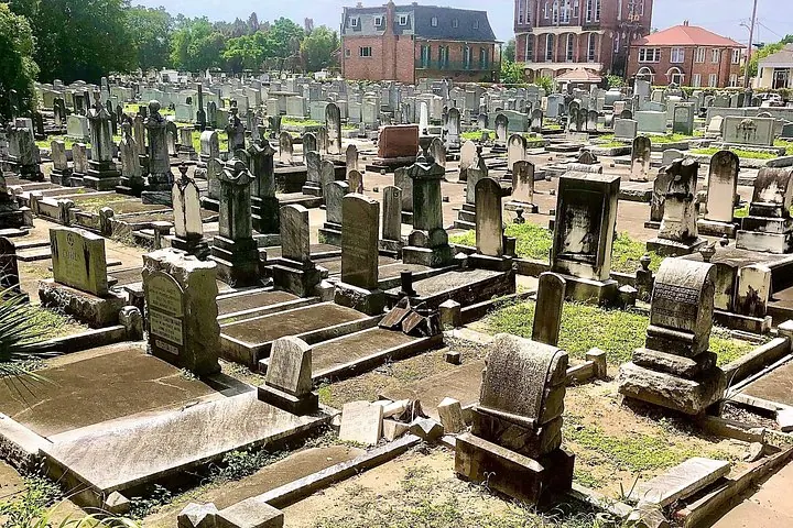 Numerous old headstones scattered across a green lawn in a historic cemetery.