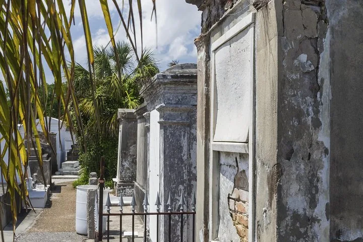 Deteriorating above-ground tombs at a cemetery on a sunny day.
